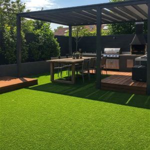 idea cesped artificial con zona de comedor y barbacoa en el jardín con Elefeme
